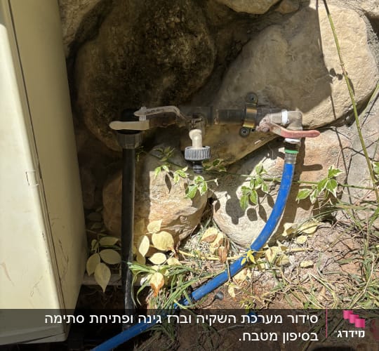 ברזים וצינורות ליד קיר אבן בגינה